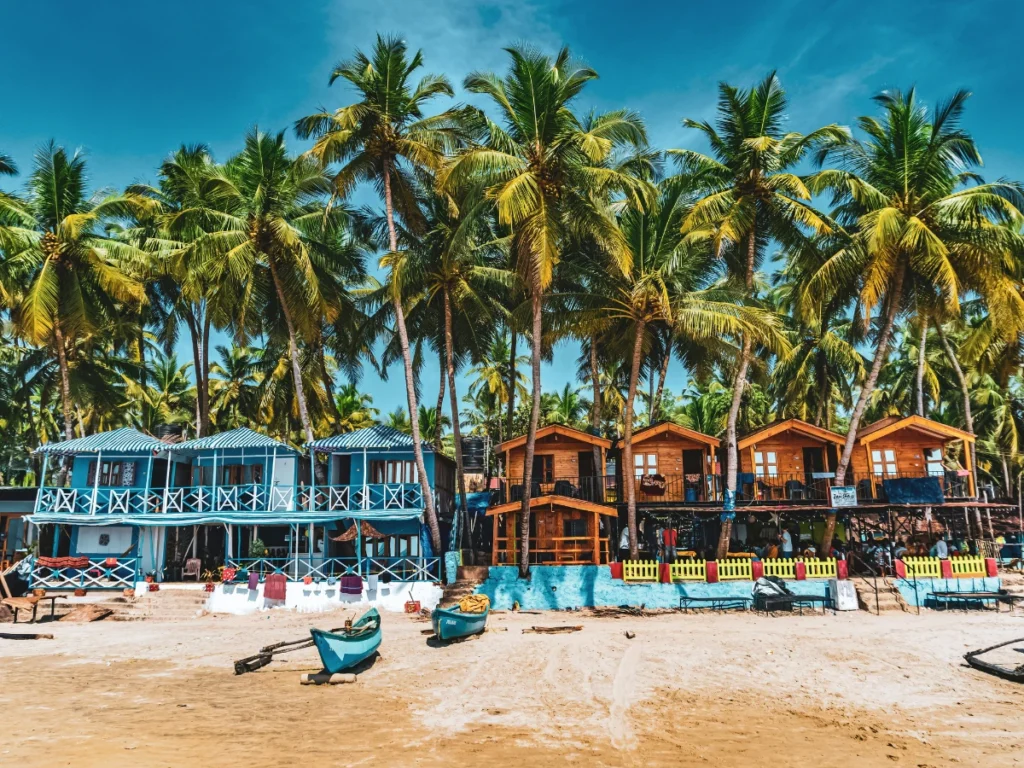 Colorful beach huts under palm trees at a scenic coastal resort in Goa, India