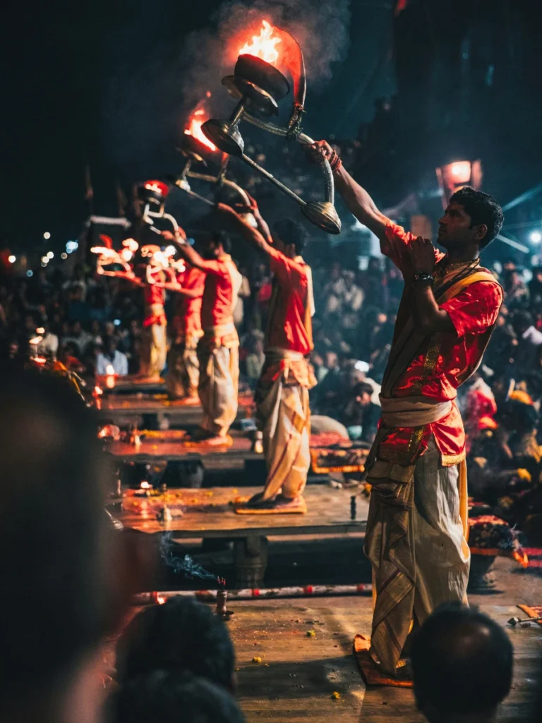 Priests performing Ganga Aarti with lit lamps on the ghats of Varanasi at night.