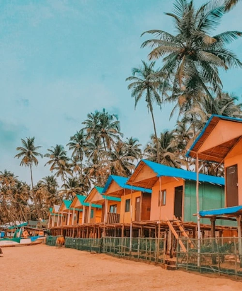 Colorful beach huts with palm trees along a tropical sandy coastline