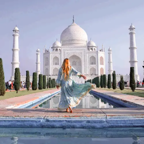 Woman in flowing dress posing in front of the Taj Mahal in Agra, India